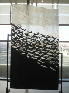 Glass screen with patterns in black, white and gold, resembling surf and seagulls.