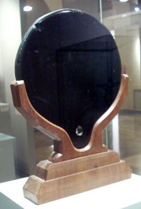 Mirror made of a deep-black polished stone, on a wooden base.