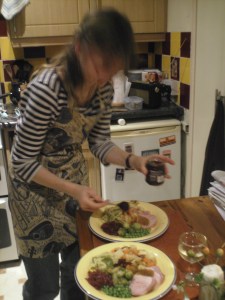 Woman with apron filling plates with roast and many different vegetables.