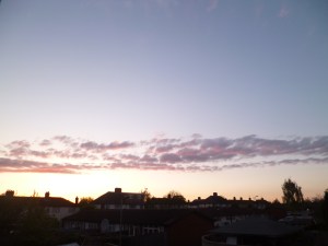 Sunset over English suburb: clear pale sky with one rack of red clouds above the roofs.