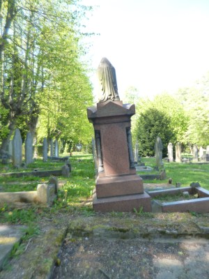 Tall tomb with urn on top, tilting, on old cemetery.